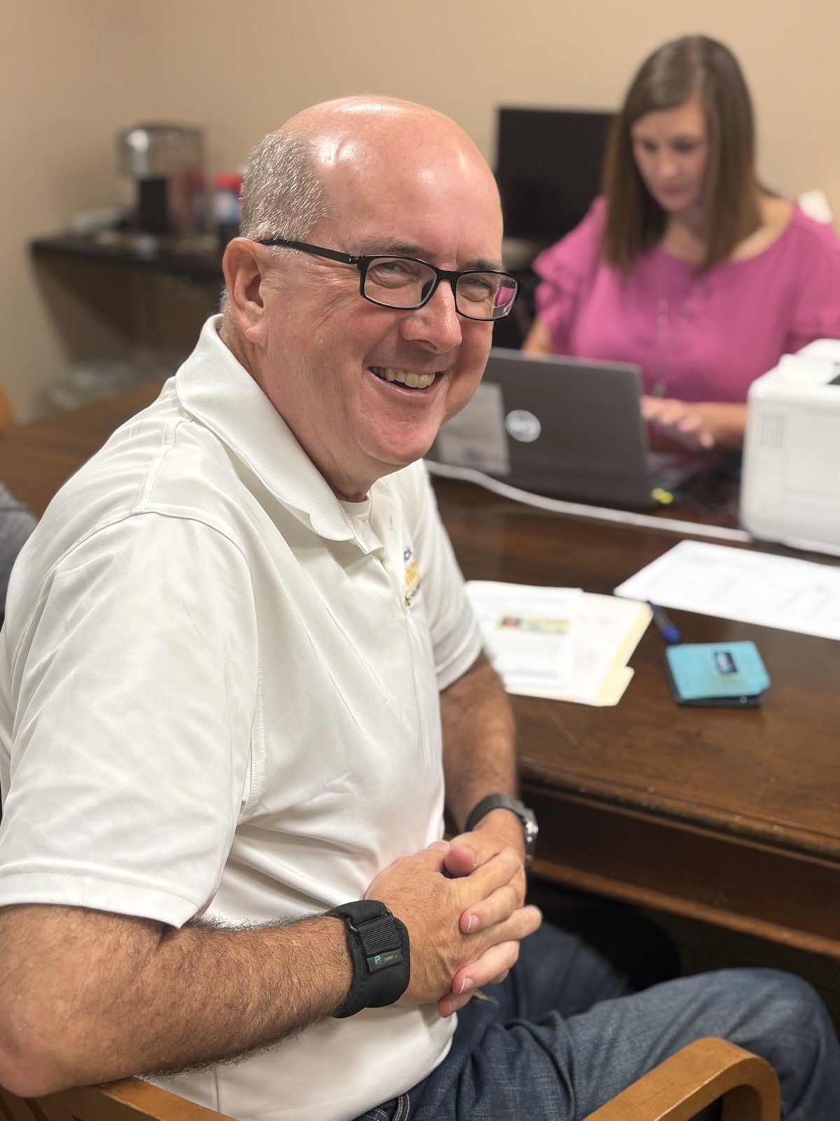 Patrick Martin smiles at the Clerk of Court's office on qualifying day, with School Board colleague Emily Soulé working at a laptop behind him.